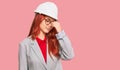 Young redhead woman wearing architect hardhat tired rubbing nose and eyes feeling fatigue and headache Royalty Free Stock Photo