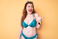 Young redhead woman wearing bikini smiling with happy face looking and pointing to the side with thumb up Royalty Free Stock Photo