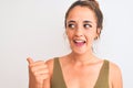 Young redhead woman wearing a bun over isolated background pointing and showing with thumb up to the side with happy face smiling Royalty Free Stock Photo