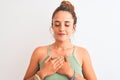 Young redhead woman wearing a bun over isolated background smiling with hands on chest with closed eyes and grateful gesture on Royalty Free Stock Photo