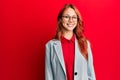 Young redhead woman wearing business jacket and glasses looking positive and happy standing and smiling with a confident smile Royalty Free Stock Photo