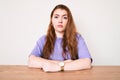 Young redhead woman wearing casual clothes sitting on the table with serious expression on face Royalty Free Stock Photo