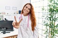 Young redhead woman wearing doctor uniform and stethoscope at the clinic smiling looking to the camera showing fingers doing Royalty Free Stock Photo