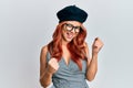 Young redhead woman wearing fashion french look with beret celebrating surprised and amazed for success with arms raised and eyes