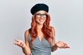 Young redhead woman wearing fashion french look with beret smiling cheerful with open arms as friendly welcome, positive and