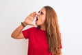 Young redhead woman wearing red casual t-shirt stading over white isolated background shouting and screaming loud to side with Royalty Free Stock Photo