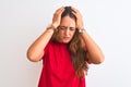 Young redhead woman wearing red casual t-shirt stading over white isolated background suffering from headache desperate and Royalty Free Stock Photo