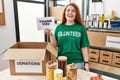 Young redhead woman wearing volunteer t shirt holding thank you banner looking positive and happy standing and smiling with a Royalty Free Stock Photo