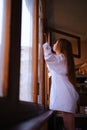 Young redhead Woman in white shirt closing The Window on the balcony Deep In Thought red hairs ginger girl general plane Royalty Free Stock Photo