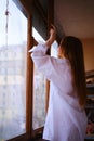 Young redhead Woman in white shirt closing The Window on the balcony Deep In Thought red hairs ginger girl general plane Royalty Free Stock Photo