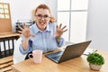 Young redhead woman working at the office using computer laptop smiling funny doing claw gesture as cat, aggressive and sexy Royalty Free Stock Photo