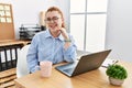 Young redhead woman working at the office using computer laptop winking looking at the camera with sexy expression, cheerful and Royalty Free Stock Photo