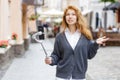 Young redheaded beautiful woman walking and using her mobile phone Royalty Free Stock Photo