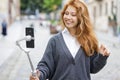 Young redheaded beautiful woman walking and using her mobile phone Royalty Free Stock Photo