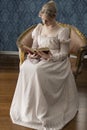 A young Regency woman in a pink dress and pearl necklace