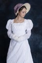 A young Regency woman wearing a white muslin dress, straw bonnet, and a pearl necklace