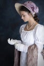 A young Regency woman wearing a white muslin dress, straw bonnet, and a pearl necklace Royalty Free Stock Photo