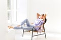 Young relaxed asian woman with closed eyes lying on chair in white empty room in front of window Royalty Free Stock Photo