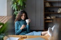 Relaxed female employee drinking coffee and using cellphone at workplace with legs on office table Royalty Free Stock Photo