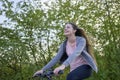 Young happily laughing woman with long hair riding a bike in beautiful greenery in springtime