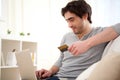 Young relaxed man paying online with credit card in sofa Royalty Free Stock Photo