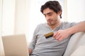 Young relaxed man paying online with credit card in sofa Royalty Free Stock Photo