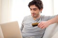 Young relaxed man paying online with credit card in sofa Royalty Free Stock Photo