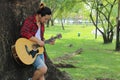 Young relaxed man is playing acoustic guitar in beautiful nature background. Royalty Free Stock Photo