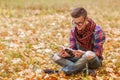 Young relaxed man reading book in nature, back on tree, meadow b