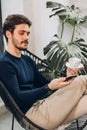 Young relaxed man using his smartphone wwhile resting on the armchair Royalty Free Stock Photo