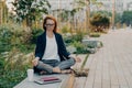 Young relaxed redhead woman meditates in park feels calm sits in lotus pose outdoor Royalty Free Stock Photo