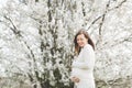 Young relaxed tender pregnant woman with closed eyes in casual clothes stroking keeping hands on belly standing in city Royalty Free Stock Photo