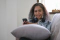 Young relaxed woman listening to the music resting on the sofa at home. Caucasian girl using smart phone and headphones for music Royalty Free Stock Photo