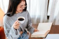 Young relaxing woman hold cup of coffee and reading a book at home