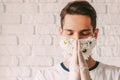 Young religious man in protective gloves and face mask praying to God