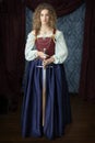 A Renaissance woman wearing a red brocade corset and blue silk skirt and holding a sword Royalty Free Stock Photo