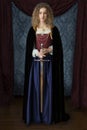 A Renaissance woman wearing a velvet cloak, a red brocade corset and blue silk skirt and holding a sword Royalty Free Stock Photo