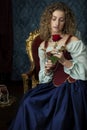 A Renaissance woman wearing a red brocade corset and blue silk skirt and holding a red rose Royalty Free Stock Photo