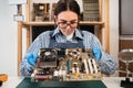 Young repairer disassembling a computer internal parts in service center. Computer female engineer working on an old