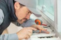 young repairman adjusting window handle with screwdriver