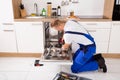 Repairman Fixing Dishwasher In Kitchen Royalty Free Stock Photo