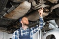 Repairman making diagnostic of raised car