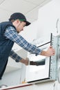 Young repairman in overall installing brand new oven in kitchen