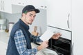 Young repairman in overall installing brand new oven in kitchen