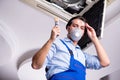 The young repairman repairing ceiling air conditioning unit Royalty Free Stock Photo