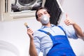 Young repairman repairing ceiling air conditioning unit Royalty Free Stock Photo