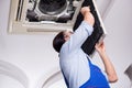 The young repairman repairing ceiling air conditioning unit Royalty Free Stock Photo