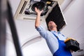 The young repairman repairing ceiling air conditioning unit Royalty Free Stock Photo