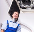 Young repairman repairing ceiling air conditioning unit Royalty Free Stock Photo
