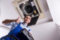 The young repairman repairing ceiling air conditioning unit Royalty Free Stock Photo